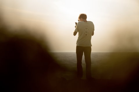 ION Vibes short-sleeve men's tee in off-white worn at the ocean coast during golden hour