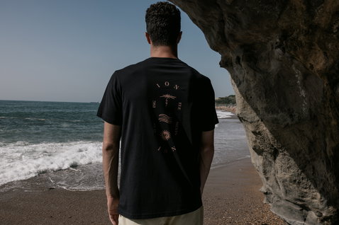 ION Bike Vibes short-sleeve tee for men in black with graphic print, back view at the beach