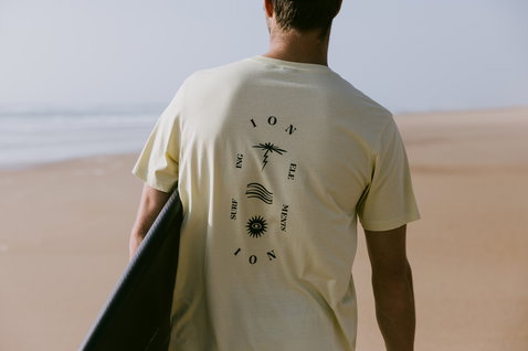 ION Vibes SS men's t-shirt in pale yellow with surf graphic on back at the beach