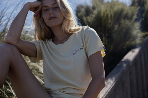 ION Vibes Damen T-Shirt in blassgelb mit Grafikprint beim Tragen an der Küste