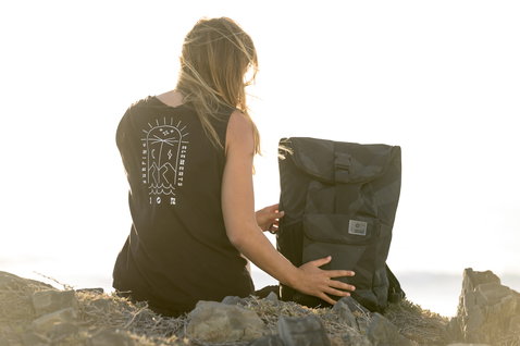 ION Mission backpack 40l in dark olive resting on coastal rocks at golden-hour sunset