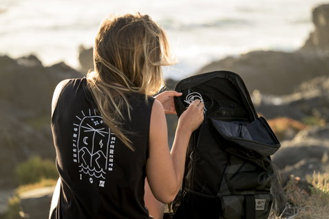 ION Mission backpack 40l in black being opened at a rocky coastal shoreline