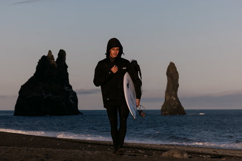 ION Neo Shelter Jacket Core giacca in neoprene in nero durante il surf sulle onde in spiaggia