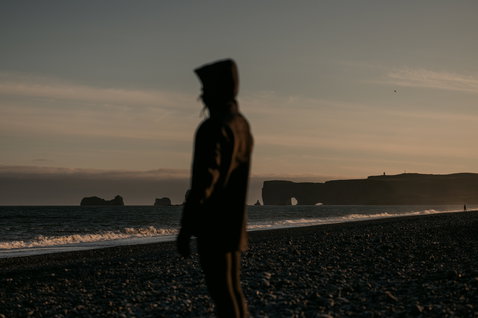 Giacca in neoprene ION Neo Shelter Jacket Core indossata su una spiaggia vulcanica al crepuscolo