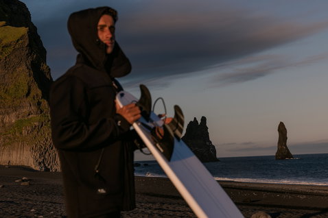 ION Neo Shelter Jacket Core uomo giacca in neoprene in nero durante wing foiling su spiaggia di sabbia nera