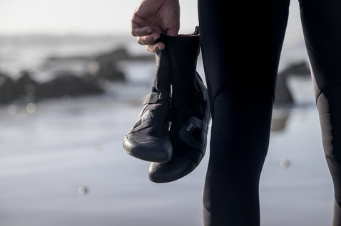 ION Ballistic Boots 3/2mm neoprene boots in black held at the ocean beach