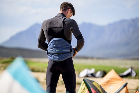 ION Rival cintura harness in blu ardesia durante il kitesurf sulla costa, vista posteriore