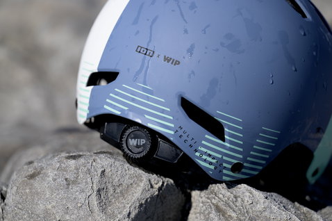 ION Slash Amp helmet in slate blue and white with 360° Fit system, side view on rocks