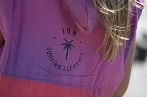 ION Poncho Select women in violet and coral with Surfing Elements logo detail view