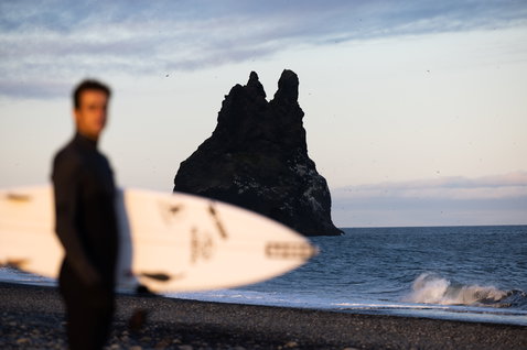 ION Seek Amp 4/3mm back-zip fullsuit wetsuit in black during wave surfing at a volcanic beach