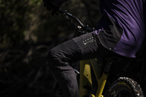 Pantaloni da ciclismo ION Scrub Amp BAT in nero durante mountain bike nel bosco