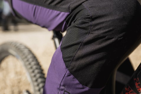 Pantaloni da ciclismo ION Scrub Amp BAT in viola e nero durante mountain bike su trail