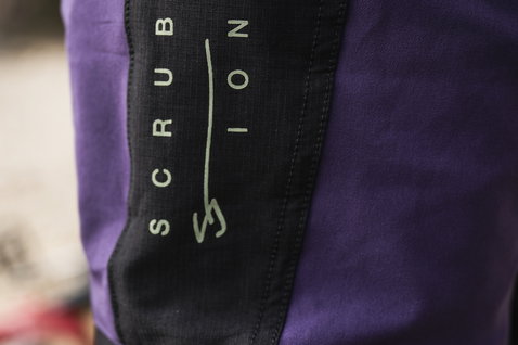 Pantaloni da ciclismo ION Scrub Amp BAT in viola e nero – dettaglio pannello laterale Cordura per freeride e downhill