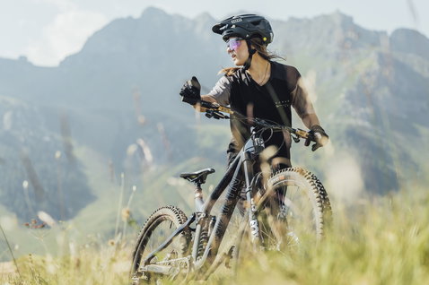 ION Scrub Amp women's short-sleeve cycling jersey in black during mountain biking in an alpine landscape