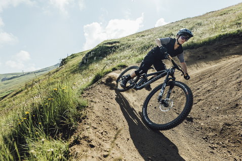 ION Scrub Amp women short-sleeve cycling jersey in dark olive during freeride mountain biking on a dirt trail
