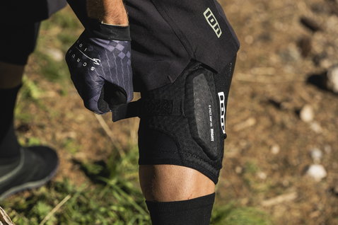 ION K-Pact Amp HD knee pads in black during mountain biking on a forest trail