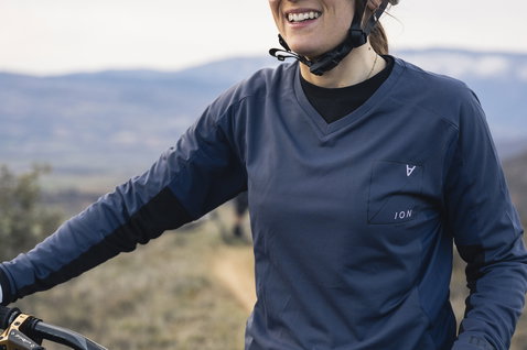 Casque VTT ION Traze Amp MIPS en gris clair lors d'une sortie trail en paysage montagneux