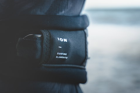 ION Arc waist harness in black with sliding wing hook, logo panel detail shot at the ocean