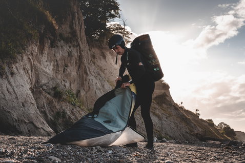 ION Wing Boardbag Core during wing foiling at a chalk cliff beach, carried as a backpack