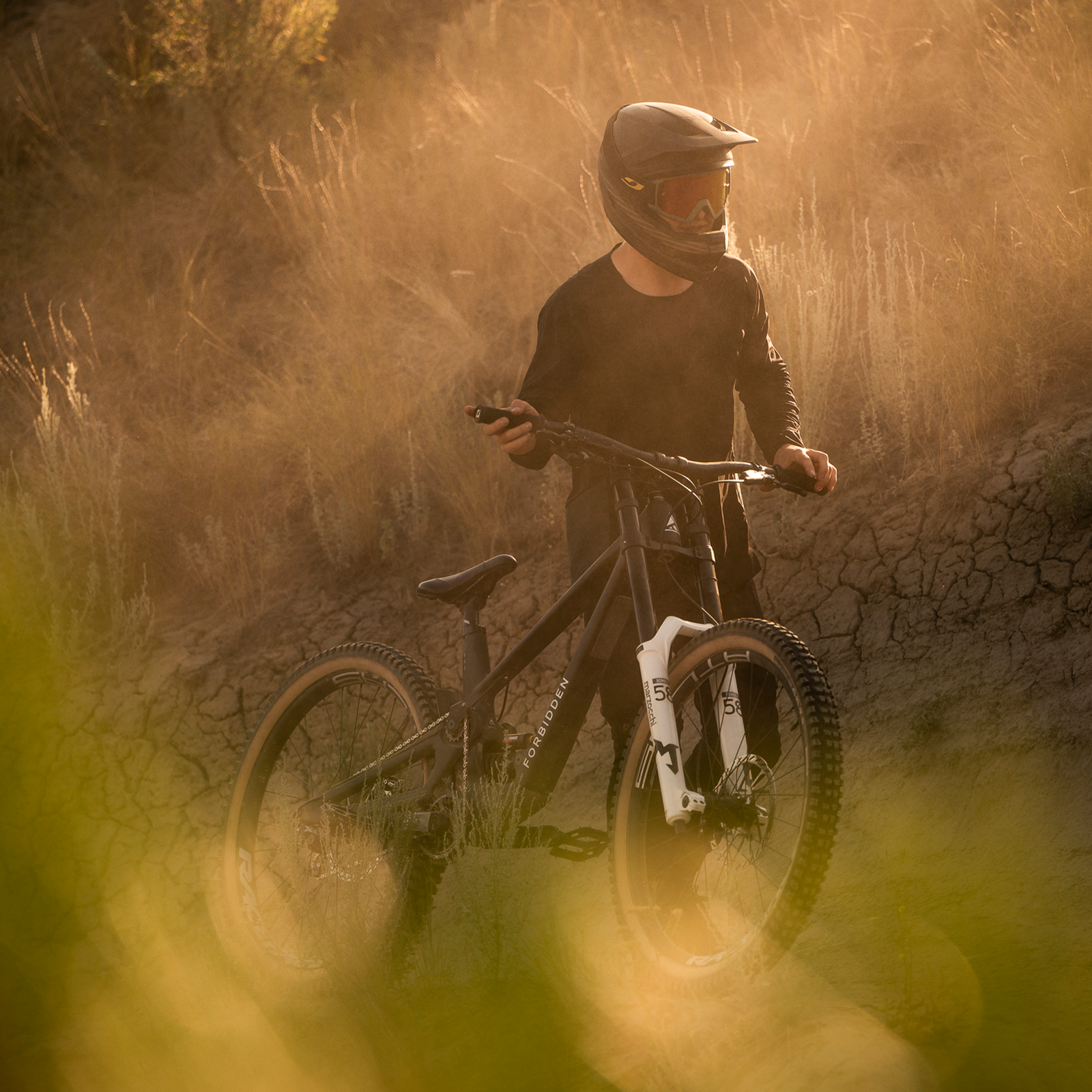 Maglia a maniche lunghe ION Scrub Amp BAT uomo in nero durante mountain bike su sterrato polveroso