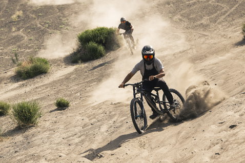 ION Bike Seek Amp cycling dungarees in charcoal during mountain biking on a dusty desert trail