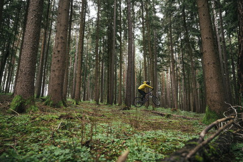 ION Shelter Lite 2.5L cycling jacket in olive green during mountain biking in the forest