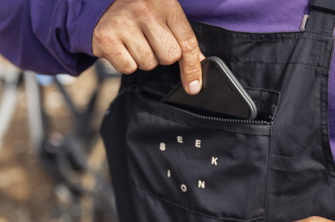ION Seek Amp cycling dungarees in black during mountain biking on a forest trail