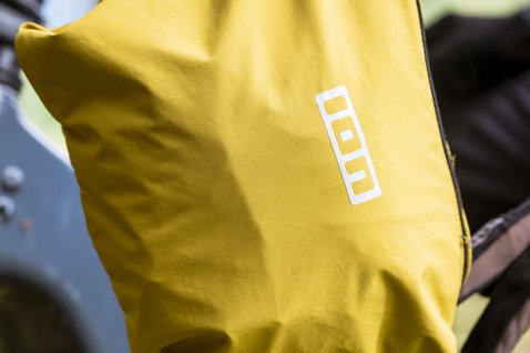 ION Shelter Lite 2.5L cycling jacket packed into stow pocket in mustard yellow for mountain biking