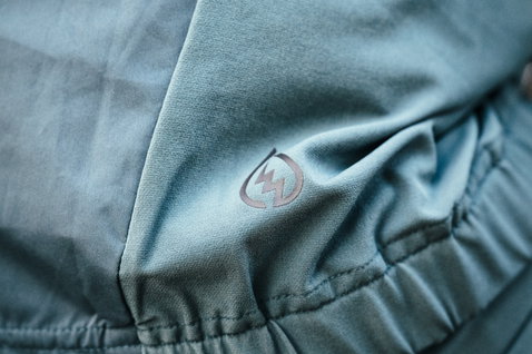 ION Shelter 3L Hybrid cycling jacket detail view of hybrid panel and hem in teal for mountain biking