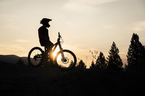 ION Bike Logo SS Herren-Radtrikot beim Mountainbiken im goldenen Abendlicht auf einem Hügel