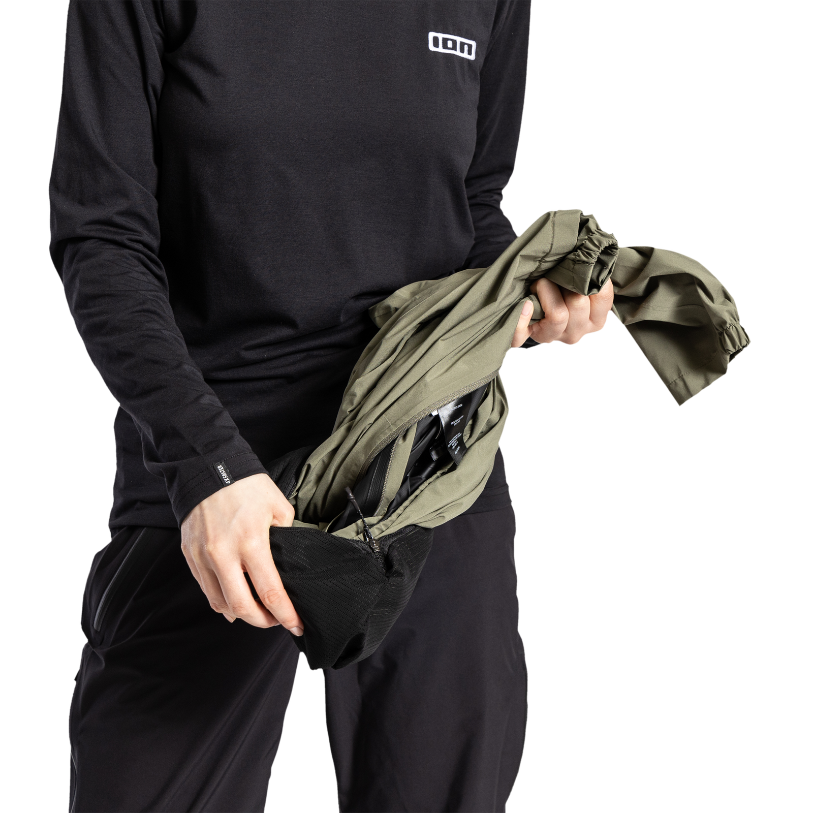 ION Shelter Anorak 2.5L cycling jacket in olive green being packed into its integrated stow pocket