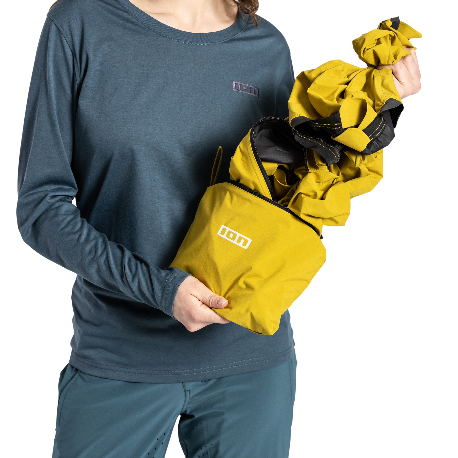 ION Shelter Lite 2.5L cycling jacket in mustard yellow packed into stow pocket for mountain biking