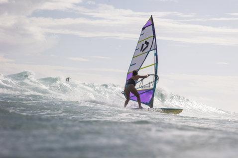 Imbracatura in vita ION Jade donna durante il windsurf sulle onde in grigio scuro con supporto Ergo_Pad