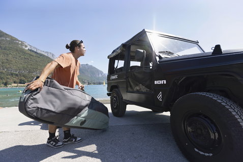 Sac ION Core Wheelie pour wakeboard 148x45 cm en gris anthracite porté au bord d'un lac de montagne