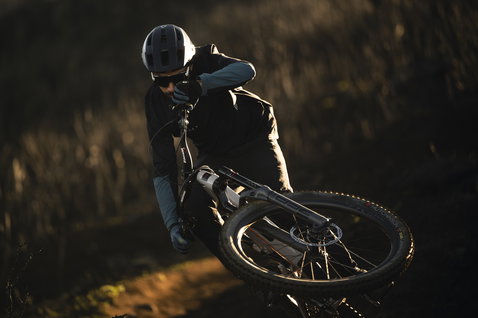 ION Traze Amp LS AFT Langarm-Bikejacke in schwarz beim Mountainbiken auf einem Naturtrail