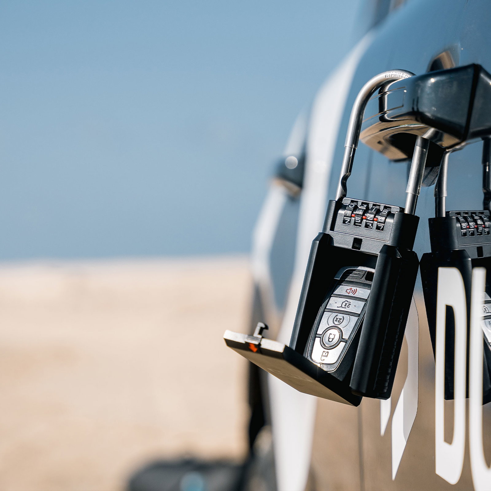 ION Keysafe combination lockbox secured to a car door handle at the beach with key fob inside