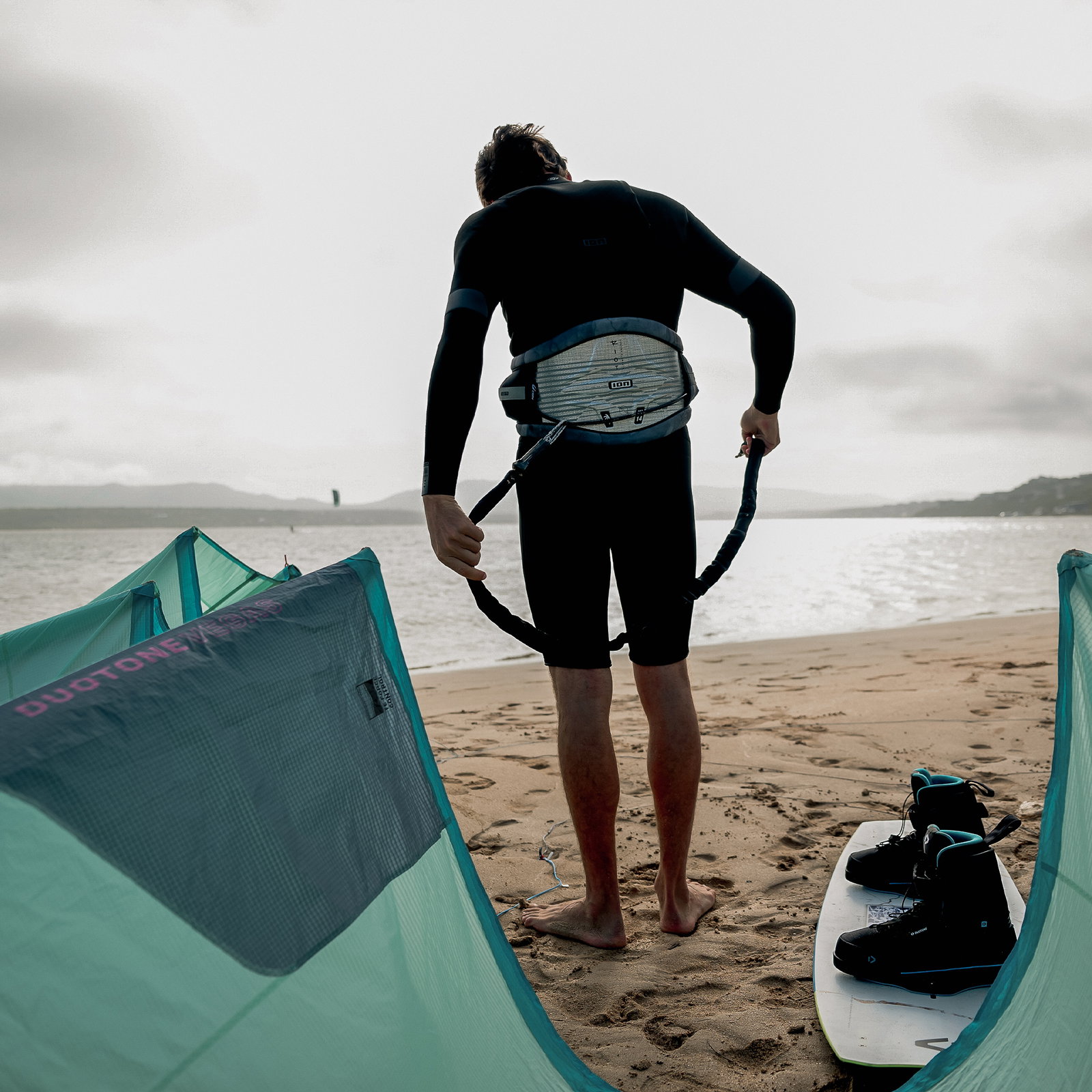ION Handle Pass Leash Comp during freestyle kitesurfing on a sandy beach