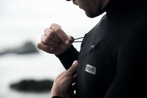 ION Seek Select 5/4mm front-zip fullsuit wetsuit in black being put on at the coast