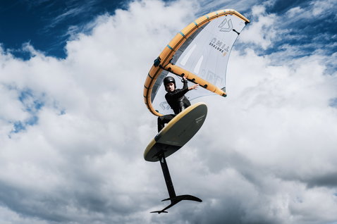 ION Wing Handle utilisé en wing foiling avec l'aile Duotone Unit sous un ciel nuageux dramatique
