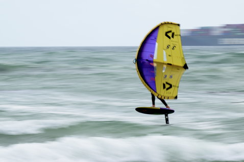 Ala foil Duotone durante il wing foiling sull'oceano in giallo e viola