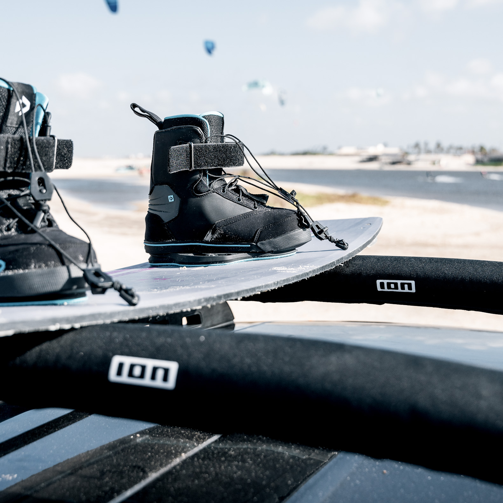 ION Roof Rack Pads 40 cm in nero con kiteboard e boots sulla spiaggia