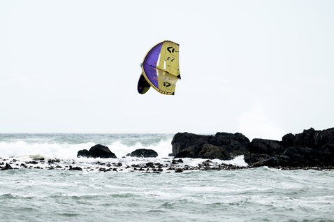 ION Wing Board Leash Core Coiled Hip Release durante il wing foiling su costa rocciosa
