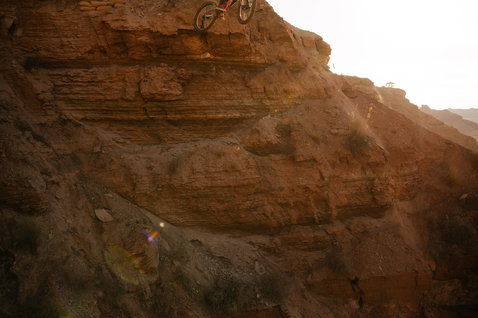 Gilet protettivo ION Amp durante una discesa estrema in mountain bike in un canyon desertico al tramonto