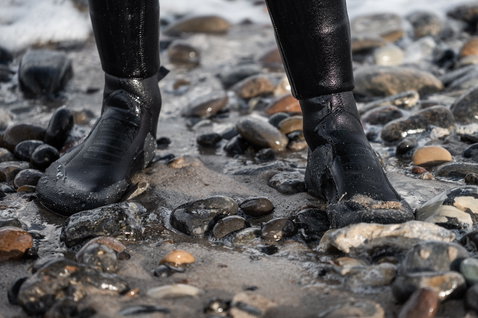 ION Plasma Boots 3/2mm round toe neoprene boots in black during kitesurfing on a rocky pebble beach
