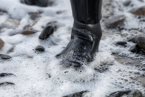 ION Plasma Boots 3/2mm neoprene boots in black during kitesurfing in surf wash on a rocky beach