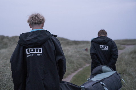 ION Storm Coat changing robe in black during a coastal beach walk