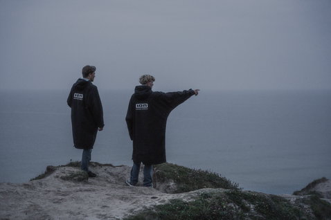 ION Storm Coat changing robe in black worn at a coastal cliff overlooking the ocean