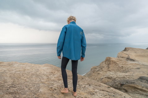 Veste néoprène ION Neo Cruise homme en bleu portée sur des falaises côtières