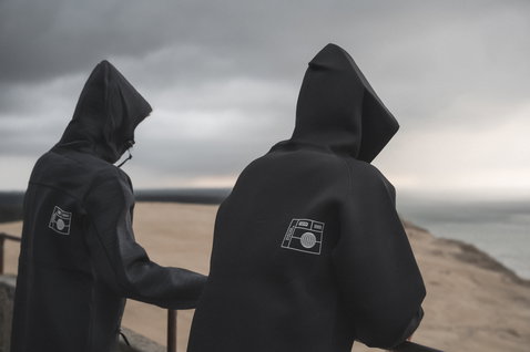 ION Neo Hoody Reversible neoprene hoodie in black worn at the coast, back view