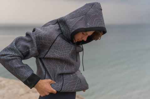 ION Neo Hoody Reversible men's neoprene hoodie in dark charcoal grey with topographic print at the coast